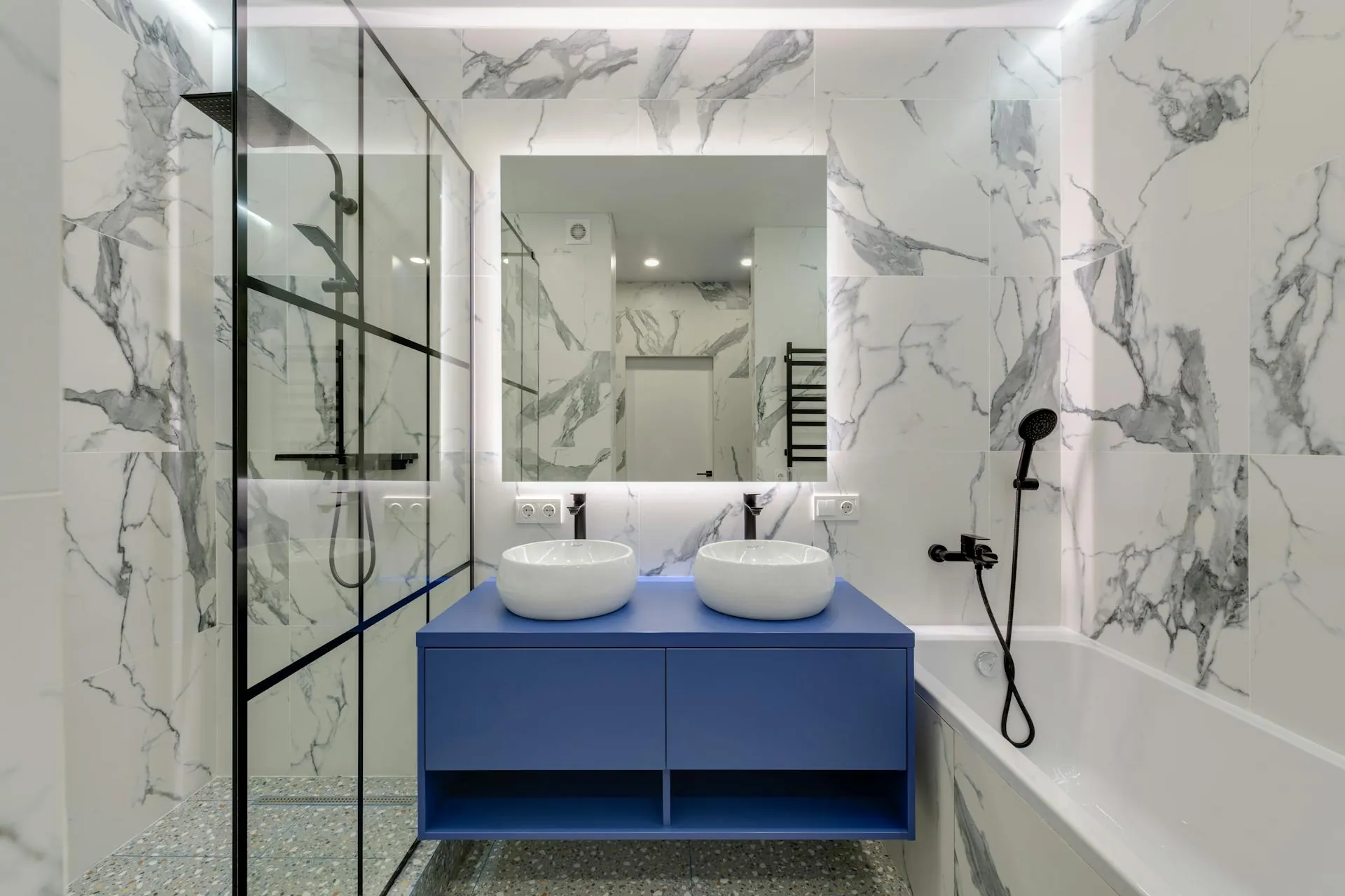 Completed bathroom renovation with blue tiling and a glass shower