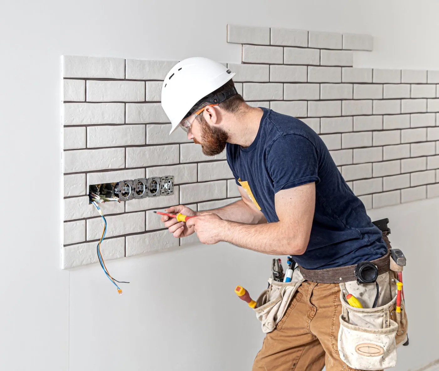 Electrician wiring sockets into a tiled kitchen wall